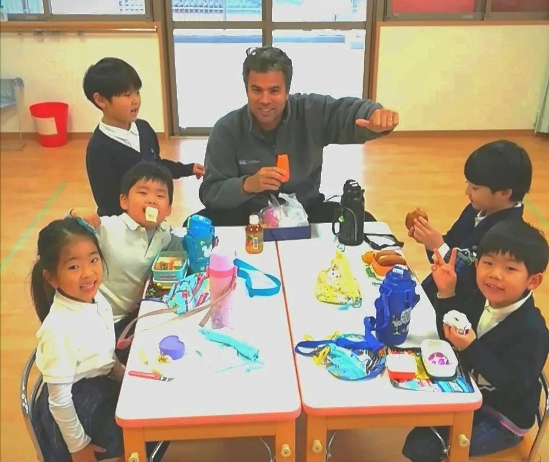 机を囲んで工作をしながら英語を学ぶ子どもたちとクリス先生